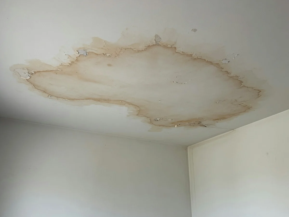 Large water stain spreading across the ceiling of a Cincinnati living room after a leak from above